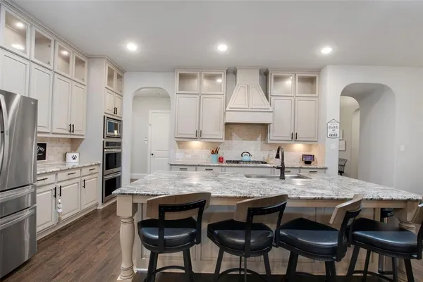 a kitchen with stainless steel appliances granite countertop a table chairs sink refrigerator and cabinets