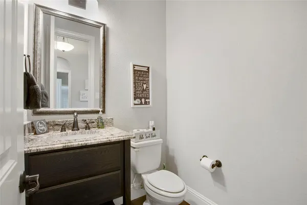a bathroom with a granite countertop sink mirror vanity and toilet