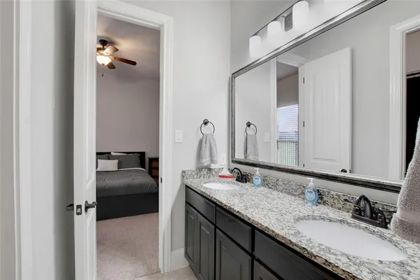 a en suite bathroom with a granite countertop sink and a mirror