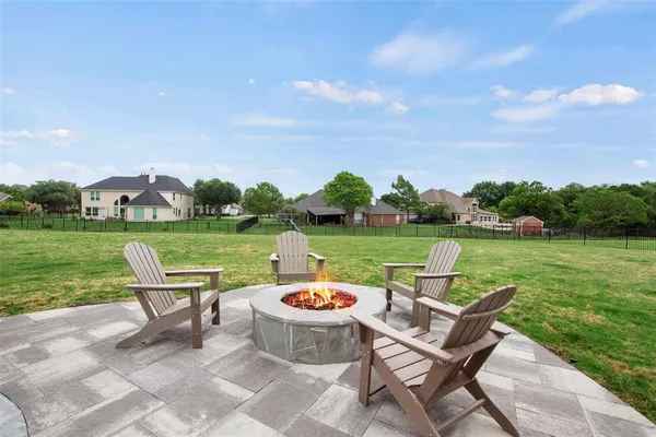a view of a lake with table and chairs with wooden fence