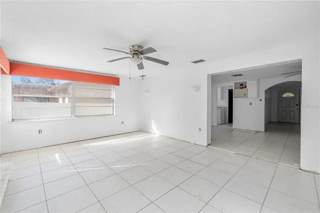 a view of an empty room with a window and a ceiling fan