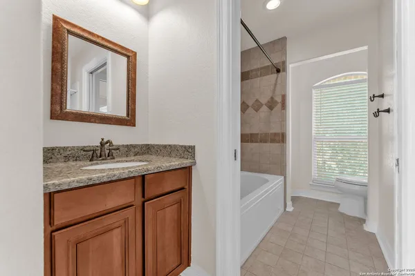 a bathroom with a granite countertop sink a mirror a vanity and a bathtub
