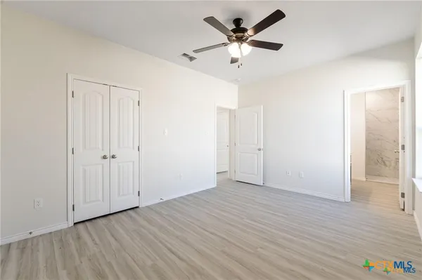 an empty room with wooden floor and ceiling fan