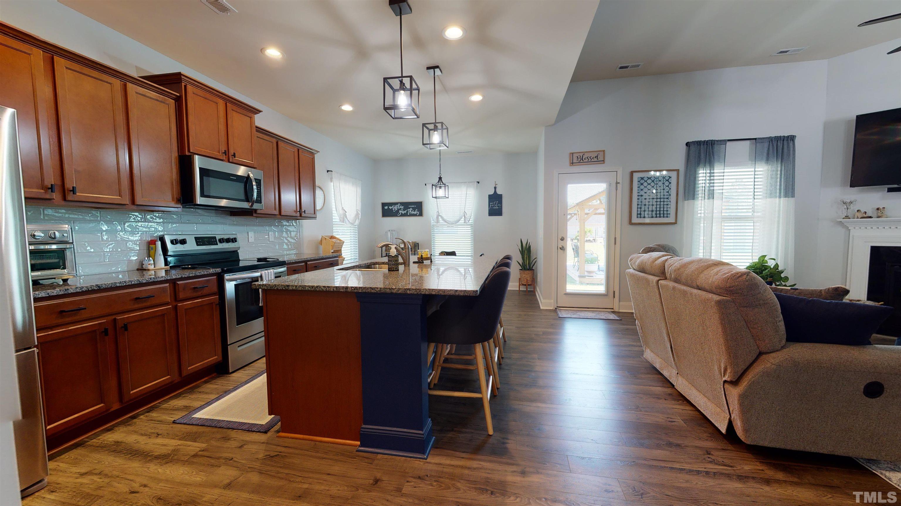 96 Longo Lane Benson, NC 27504 - Photo 8 of 51 a kitchen with stainless steel appliances granite countertop wooden floors wooden cabinets dining table and chairs