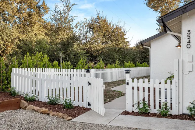 a white house that has tree in front of it