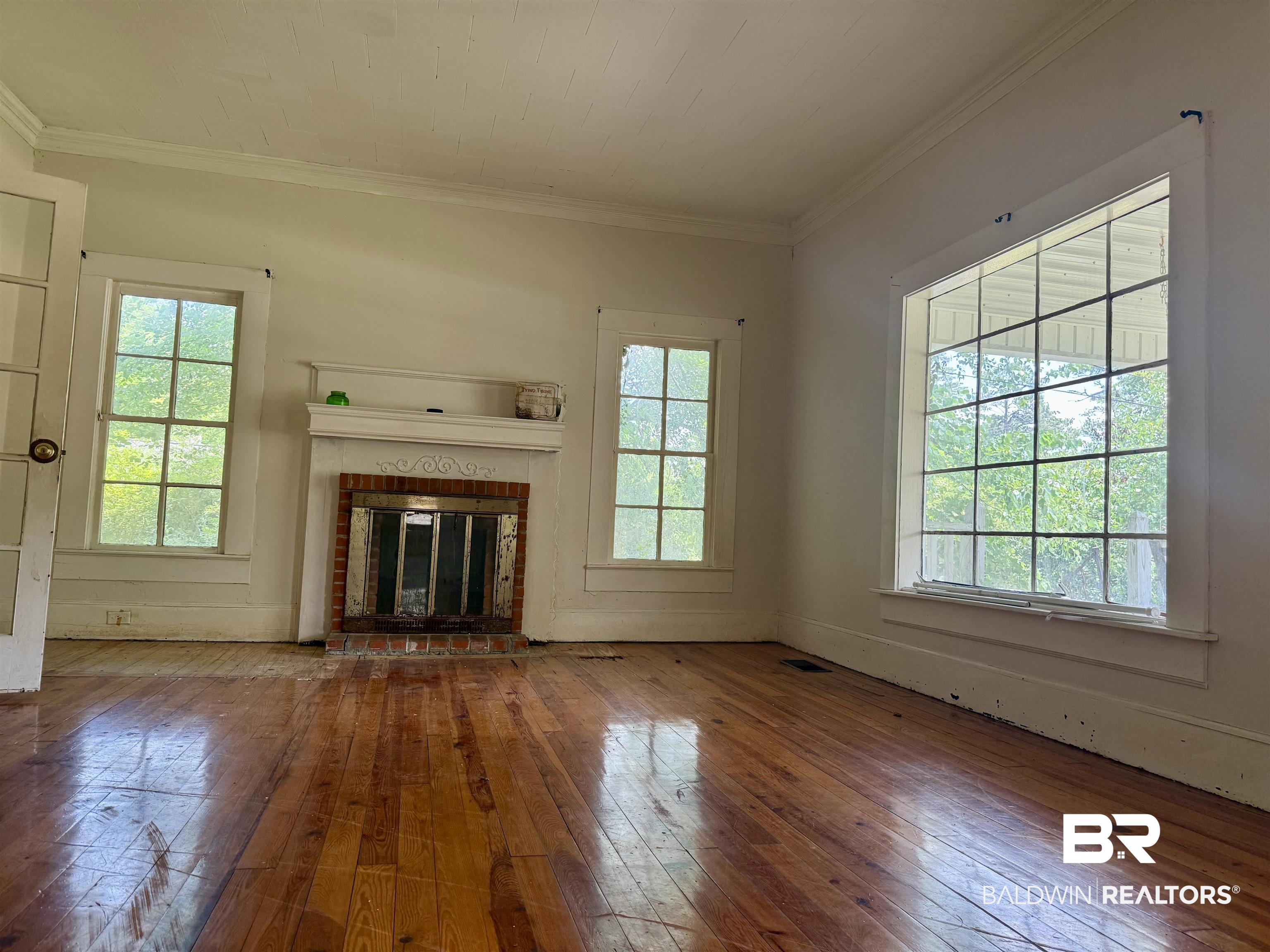 610 Alco Drive Brewton, AL 36426 - Photo 12 of 18 Unfurnished living room with hardwood / wood-style floors, plenty of natural light, a brick fireplace, crown molding, and baseboards