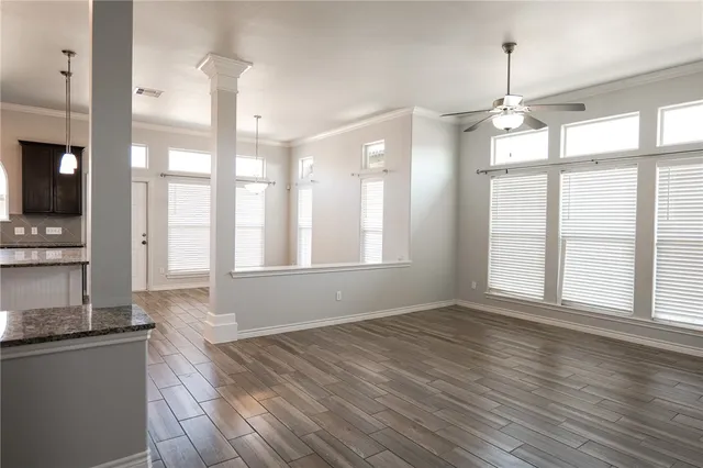 a view of an empty room with a window and wooden floor