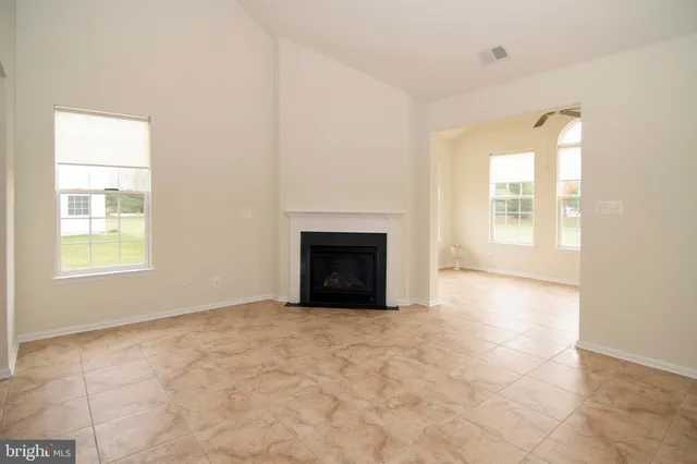 an empty room with chandelier fan and windows