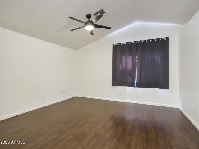 an empty room with a ceiling fan and wooden floor