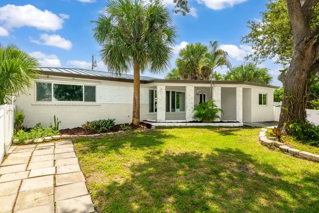 a white house with a large pool yard and palm trees