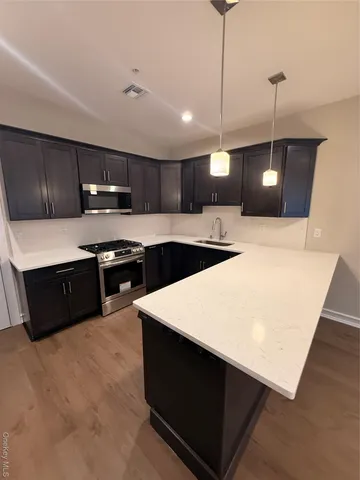 a kitchen with stainless steel appliances granite countertop a sink a stove top oven a counter space and cabinets