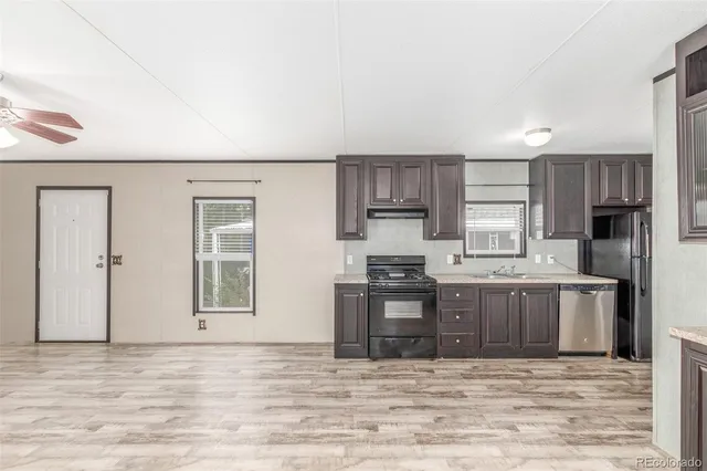 a view of a kitchen with stainless steel appliances granite countertop a stove top oven a sink dishwasher a microwave oven and a refrigerator with wooden floor