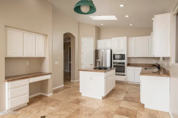 a kitchen with a refrigerator a stove top oven a sink dishwasher and white cabinets with wooden floor