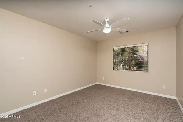 an empty room with a fan & a ceiling fan
