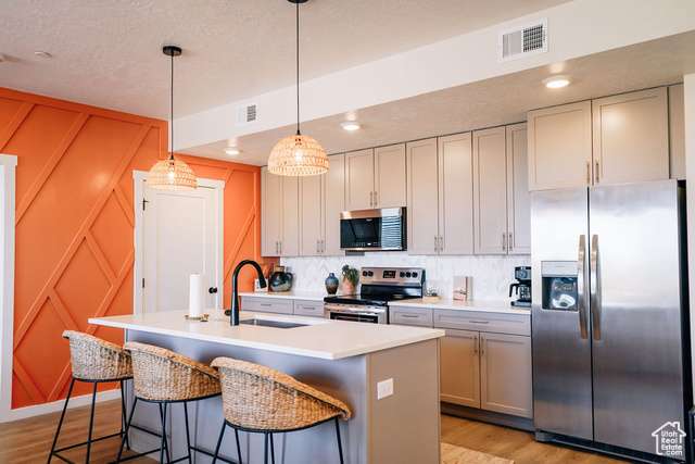 961 West Akoya Pearl Road, Unit 201 St. George, UT 84790 - Photo 10 of 67 Kitchen with stainless steel appliances, light wood-style flooring, a textured ceiling, light countertops, and an island with sink