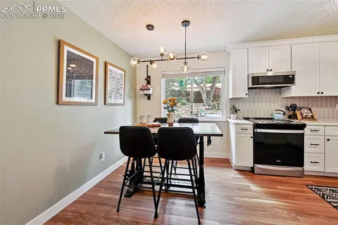 a kitchen with stainless steel appliances granite countertop a stove a refrigerator a sink dishwasher a dining table and chairs with wooden floor