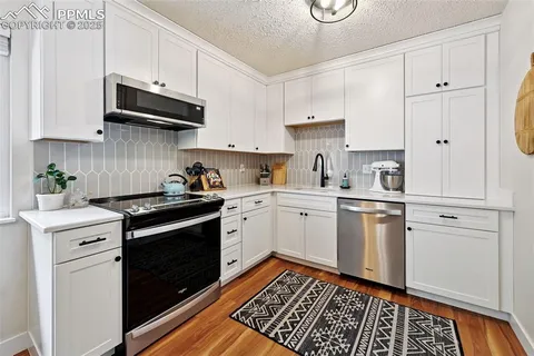 a kitchen with granite countertop white cabinets and white appliances