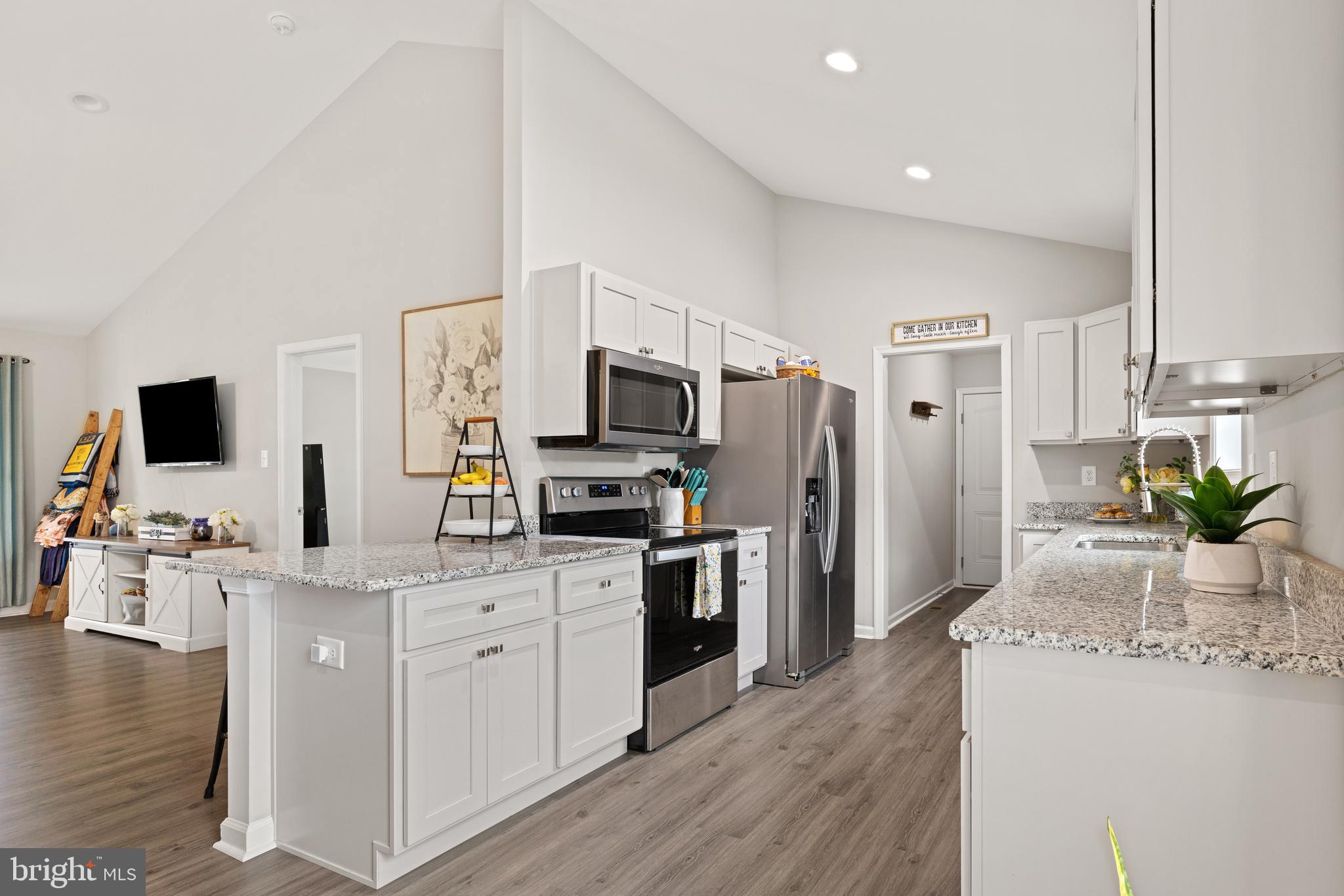 61 MDG Court Berkeley Springs, WV 25411 - Photo 31 of 47 a kitchen with stainless steel appliances a stove top oven a refrigerator a sink dishwasher and white cabinets with wooden floor