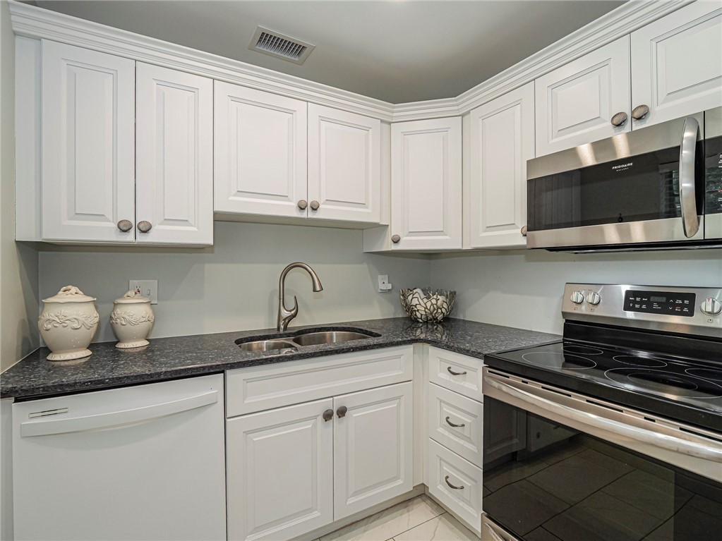 5400 Highway A1a, Unit D3 Vero Beach, FL 32963 - Photo 10 of 35 a kitchen with granite countertop white cabinets and stainless steel appliances