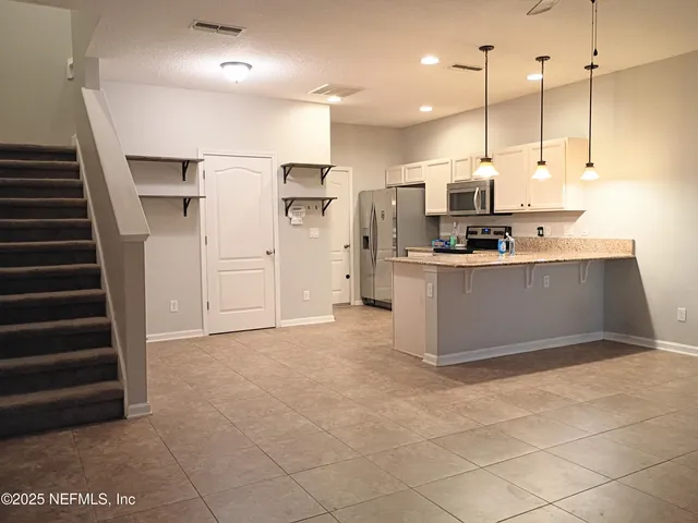 a kitchen with stainless steel appliances kitchen island granite countertop a refrigerator a stove and a sink with wooden floor