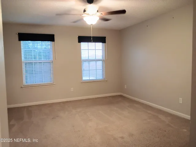 an empty room with windows and fan