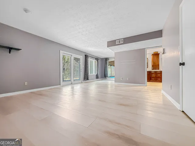 a living room with furniture and a dresser next to a window