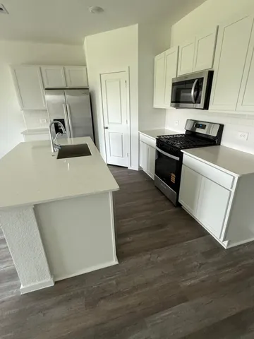 a kitchen with kitchen island a sink dishwasher stove and microwave with wooden floor