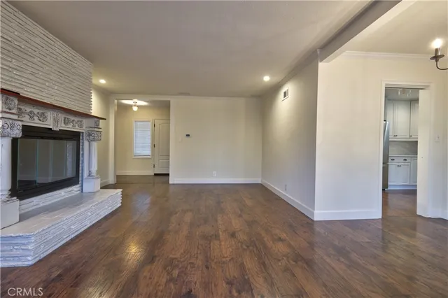 a view of an empty room with wooden floor and a fireplace