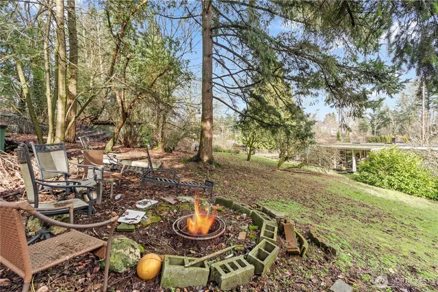 a view of a backyard with table and chairs with wooden fence and plants