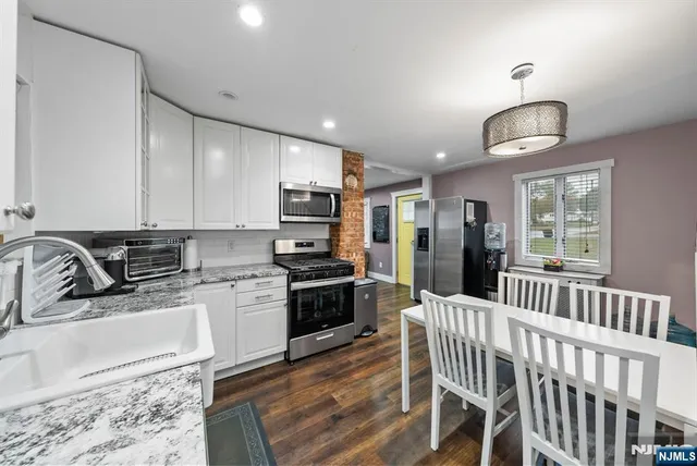 a kitchen with stainless steel appliances granite countertop a stove a sink dishwasher a dining table and chairs with wooden floor