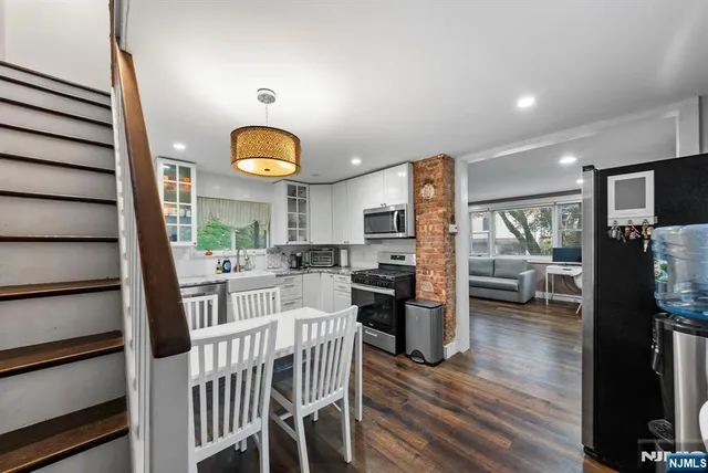 a kitchen with stainless steel appliances granite countertop a refrigerator oven stove a island and chairs with wooden floor