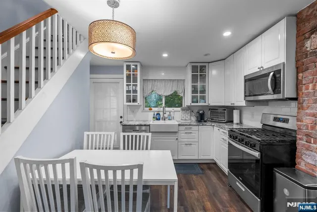 a kitchen with stainless steel appliances granite countertop a stove top oven a sink dishwasher a dining table and chairs with wooden floor