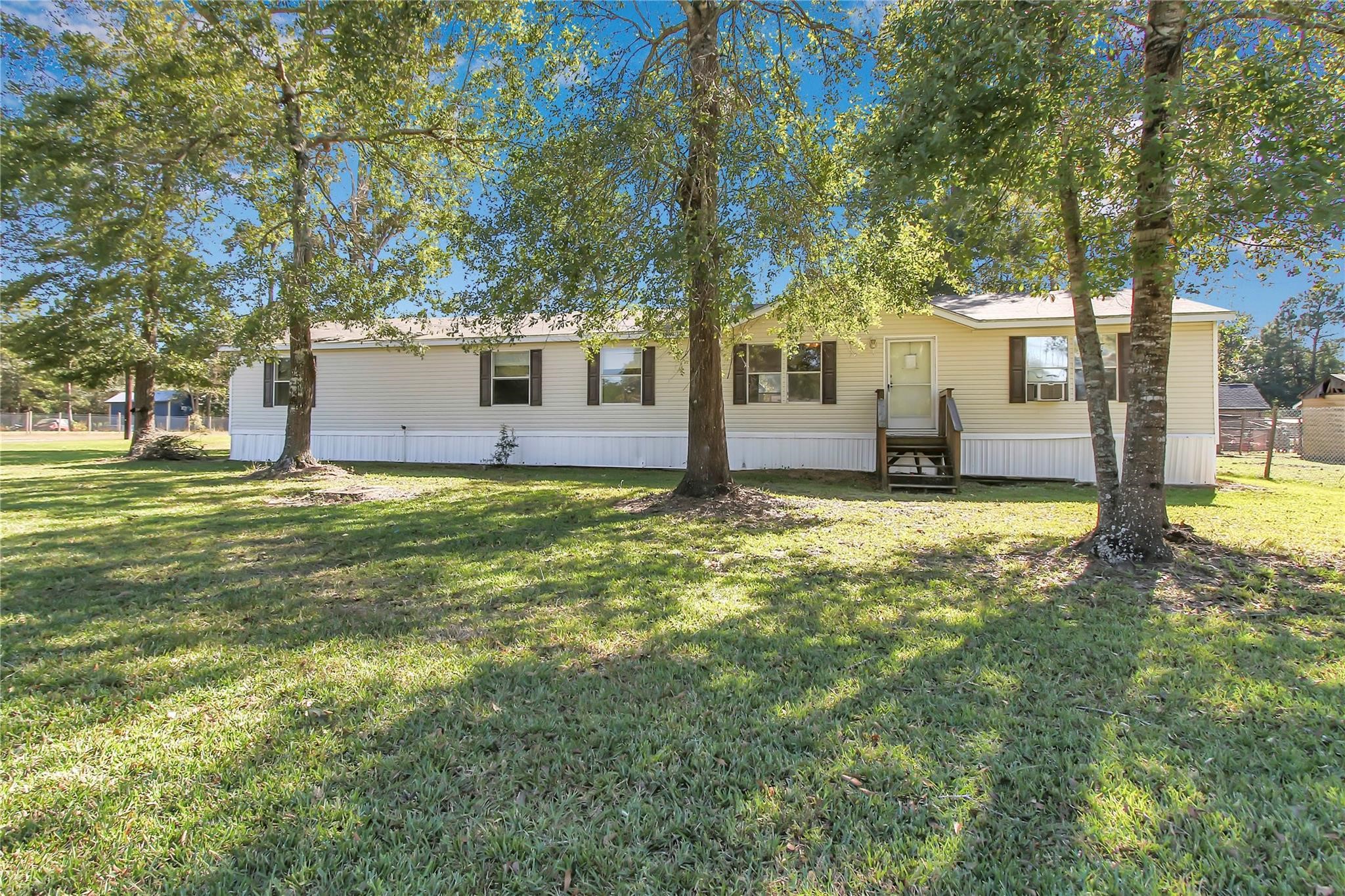 23596 Goode Road Cleveland, TX 77328 - Photo 2 of 14 a view of a house with a big yard and large tree
