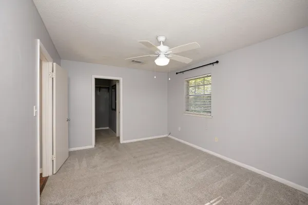 an empty room with chandelier fan and windows