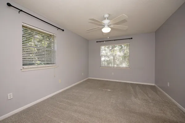 an empty room with windows and fan