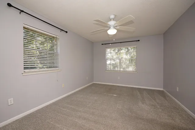 an empty room with windows and fan