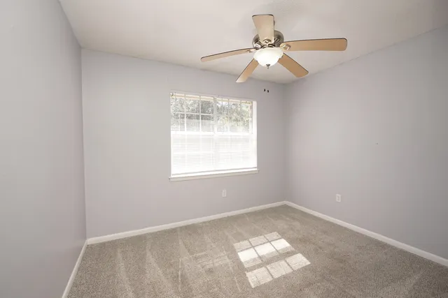 an empty room with windows and fan