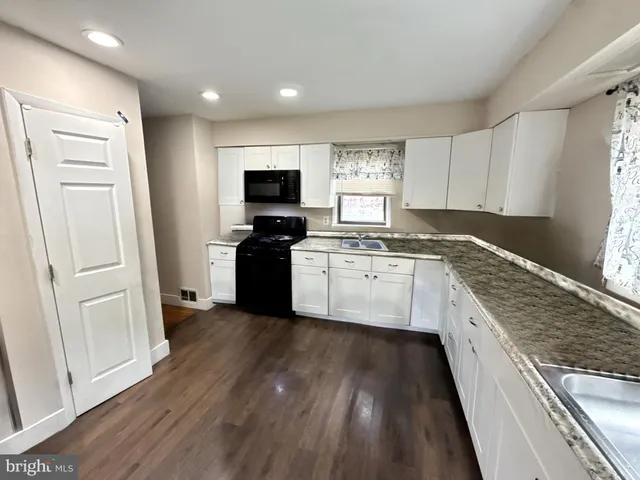 a large kitchen with cabinets wooden floor and stainless steel appliances