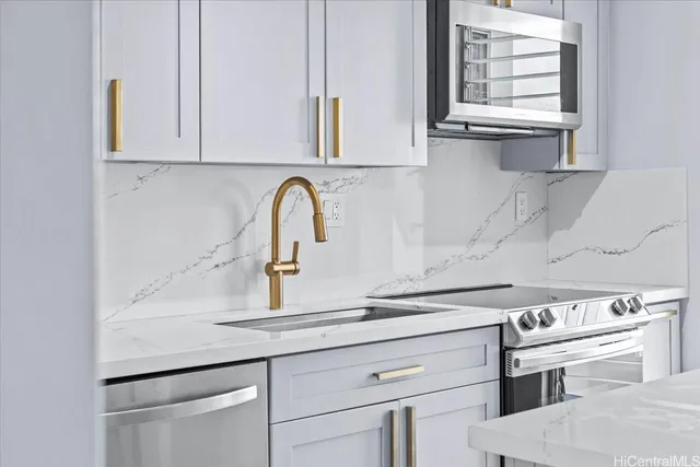 a close view of a stove a sink and dishwasher with white cabinet