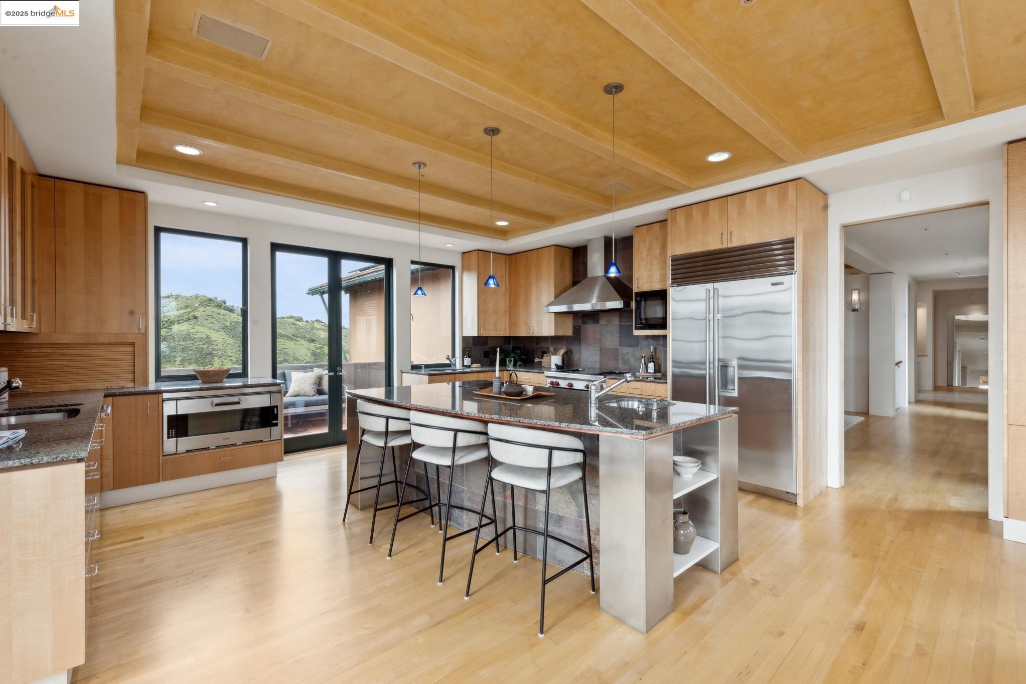 5 Woodside Way Oakland, CA 94611 - Photo 17 of 59 a kitchen with stainless steel appliances kitchen island granite countertop a stove a refrigerator a sink a dining table and chairs with wooden floor