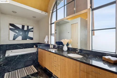 a bathroom with a granite countertop tub sink and mirror