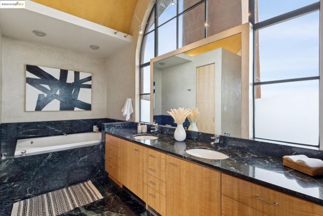 a bathroom with a granite countertop tub sink and mirror