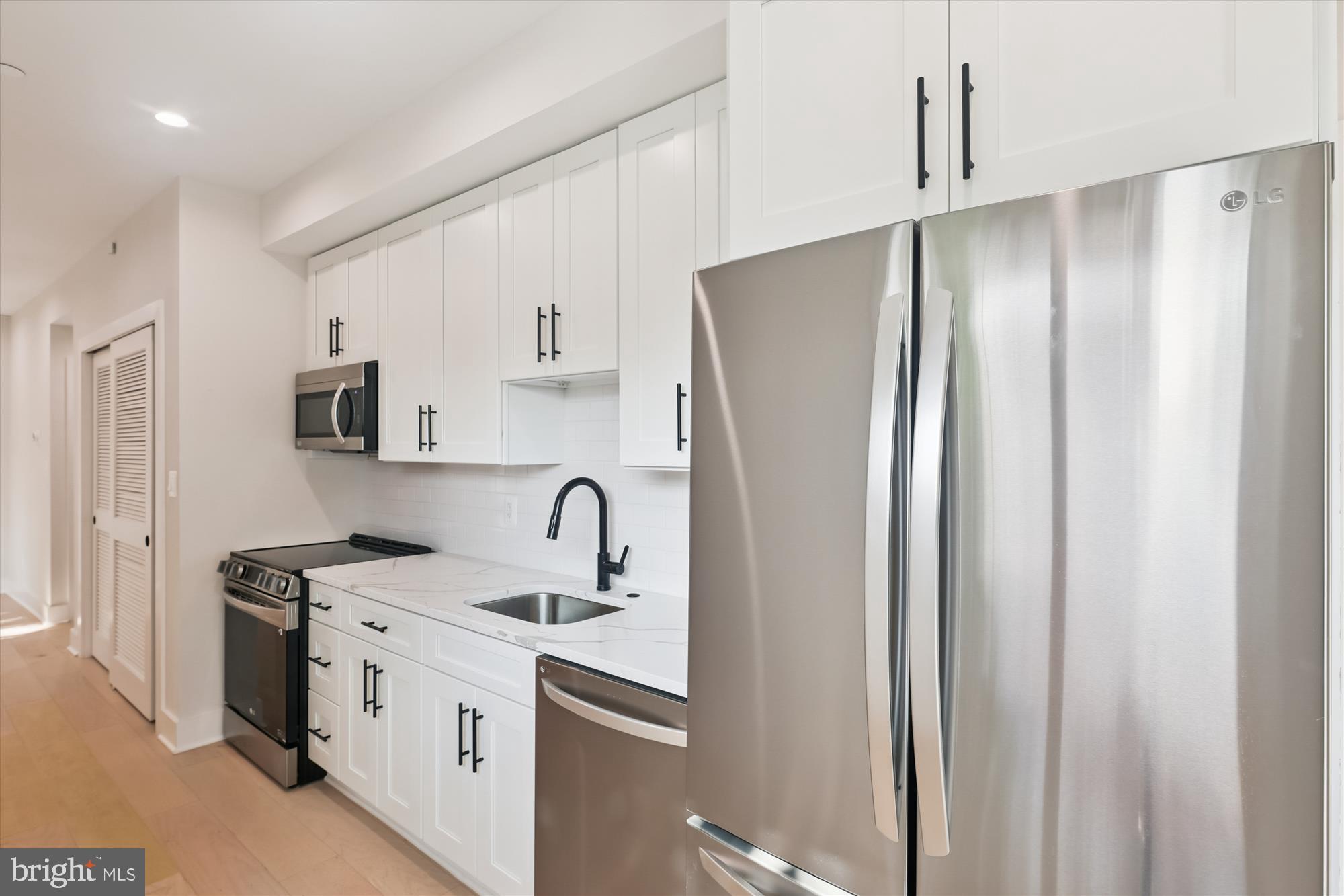 1910 Benning Road Northeast, Unit 2 Washington, DC 20002 - Photo 4 of 19 a kitchen with stainless steel appliances a refrigerator sink and white cabinets