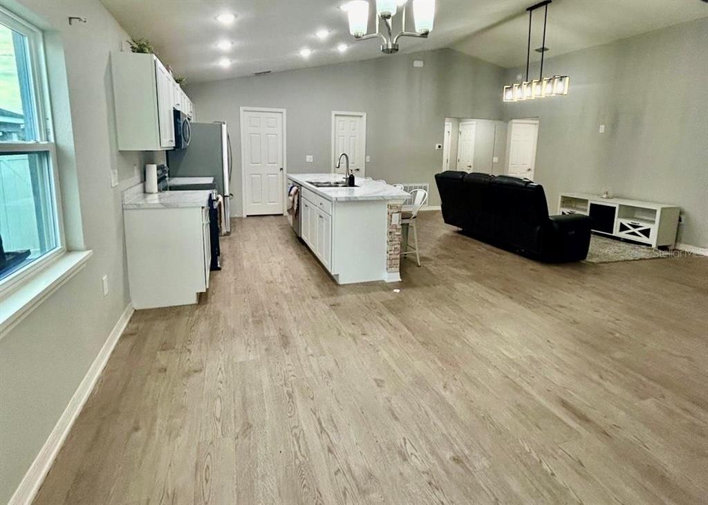 4098 Ruby Run Haines City, FL 33844 - Photo 13 of 34 a kitchen with stainless steel appliances kitchen island granite countertop a refrigerator a stove top oven a sink dishwasher and wooden floor