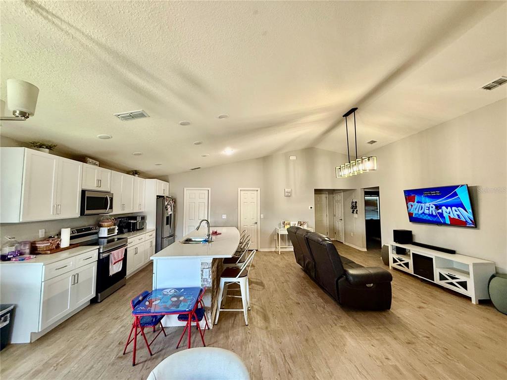 4098 Ruby Run Haines City, FL 33844 - Photo 14 of 34 a living room with furniture a rug kitchen view and a chandelier