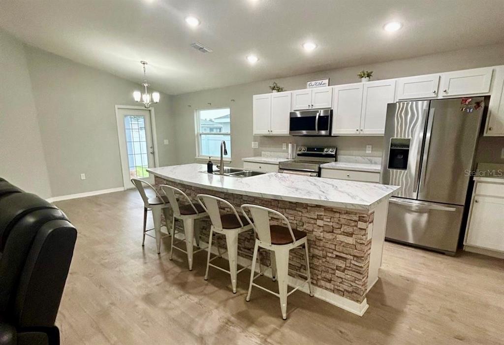 4098 Ruby Run Haines City, FL 33844 - Photo 15 of 34 a kitchen with stainless steel appliances granite countertop a table chairs sink refrigerator and microwave
