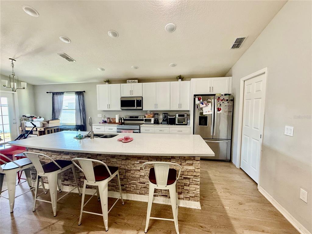 4098 Ruby Run Haines City, FL 33844 - Photo 19 of 34 a kitchen with stainless steel appliances kitchen island granite countertop a table chairs microwave and refrigerator