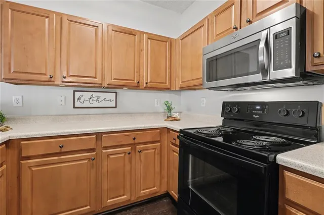 a kitchen with stainless steel appliances granite countertop white cabinets and a stove top oven