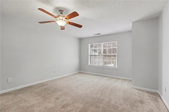 a view of an empty room with a ceiling fan and window