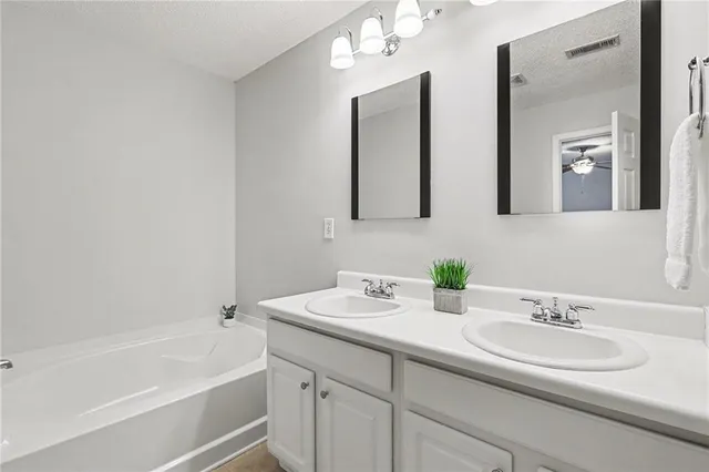 a bathroom with a sink double vanity granite tub and a mirror